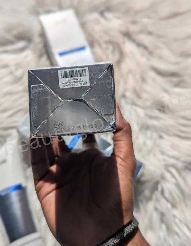 Hand holding a small rectangular box with a label on a textured surface