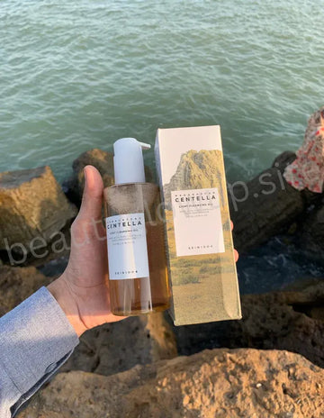 Hand holding a bottle and box of Centella by the water