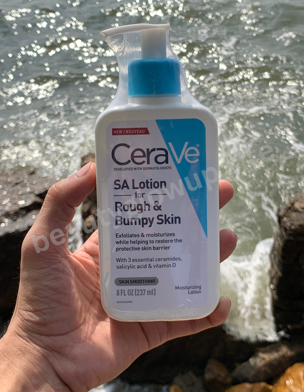 CeraVe SA Lotion for Rough & Bumpy Skin held in front of a water background