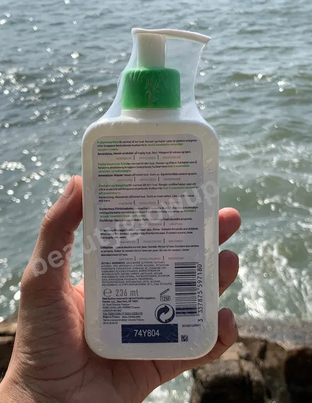 CeraVe hydrating cleanser bottle held in front of a body of water