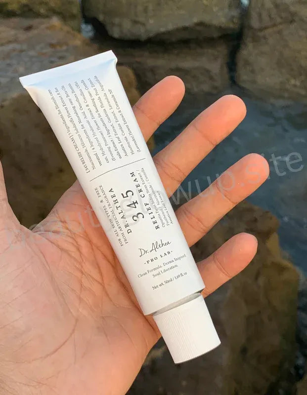 Hand holding a tube of Dr. Althea cream with a natural background