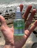 Hand holding a bottle of Anua 10+ serum with a beach background