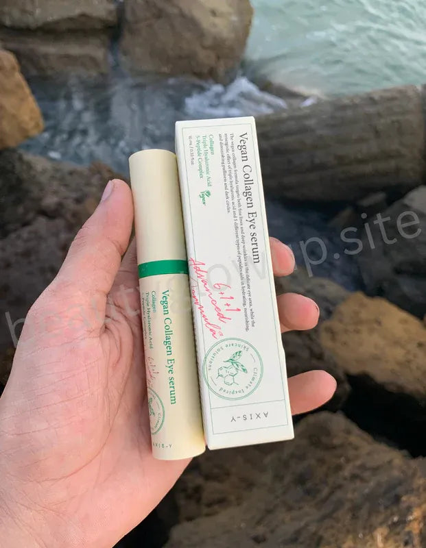 AXIS-Y Vegan Collagen Eye Serum 30ml Korean eye care product held by hand with seaside background