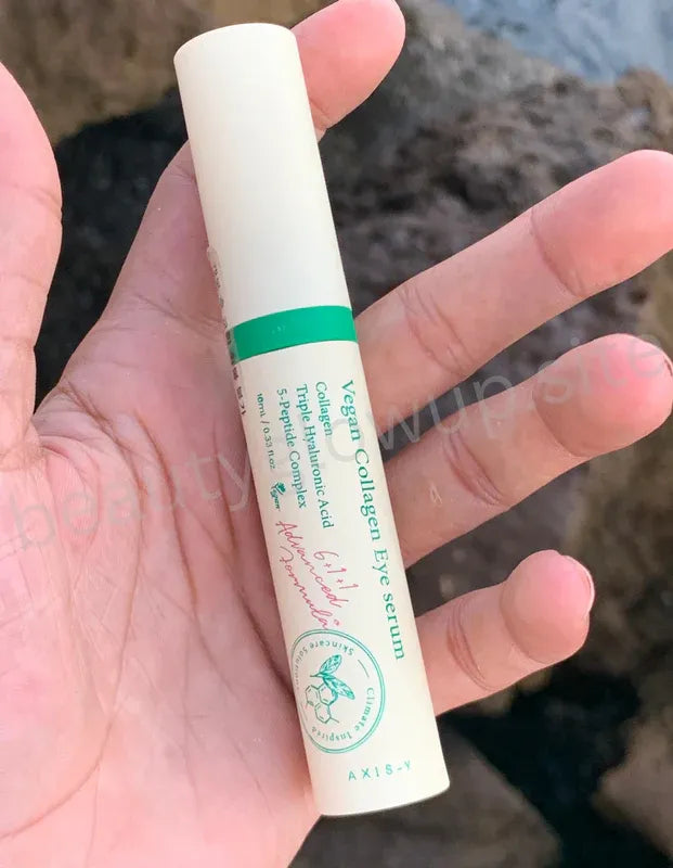 AXIS-Y Vegan Collagen Eye Serum 30ml Korean eye care product held by hand with seaside background