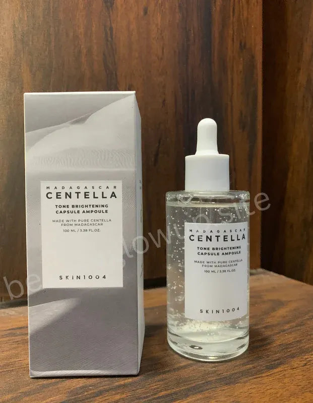 Hand holding a skincare bottle labeled 'SKIN1004' with a natural background