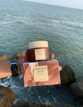 Hand holding a Skinceuticals Centella product with ocean view