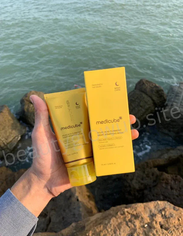 Hand holding two yellow Medicube products against a natural background