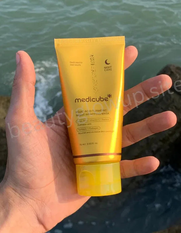 Hand holding two yellow Medicube products against a natural background